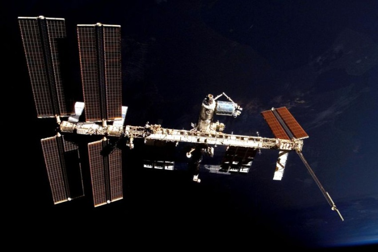 Abb.: Die Internationale Raumstation ISS und das hier hellblau reflektierende...